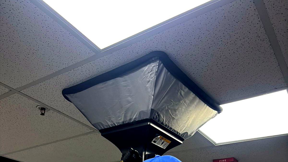 Balometer hood measuring airflow at an office ceiling diffuser